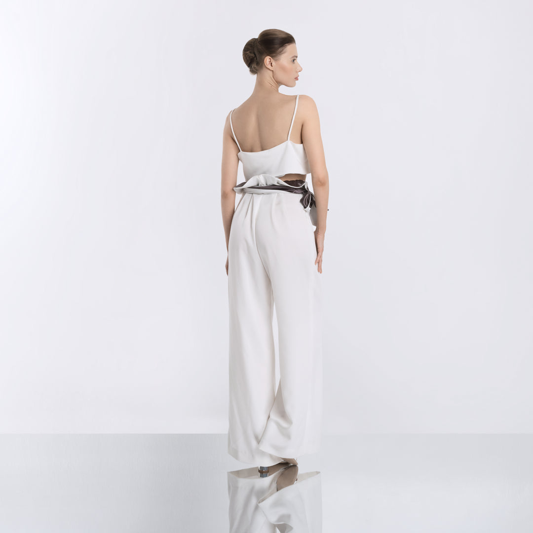 Back view of minimalist white crop top paired with high-waisted wide-leg pants and a black satin sash