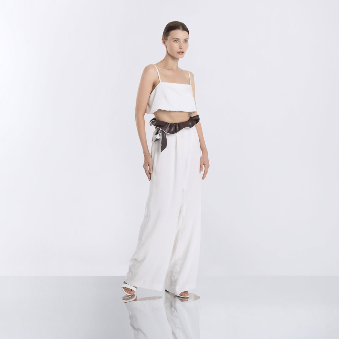 Minimalist white crop top paired with high-waisted wide-leg pants and a black satin sash, front view.