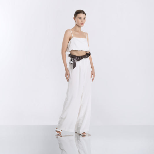 Minimalist white crop top paired with high-waisted wide-leg pants and a black satin sash, front view.