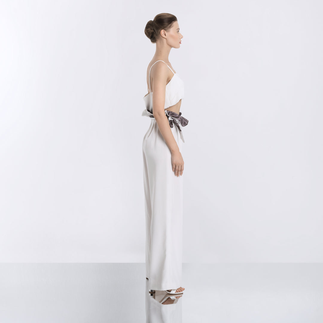 Side view of a minimalist white two-piece outfit featuring a crop top and flowing wide-leg pants with a satin sash.