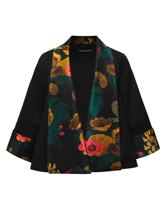 Front view of a reversible black brocade kimono-style jacket with wide sleeves and a structured silhouette, designed by Lola Clavel. Fully lined in contrasting floral jacquard.