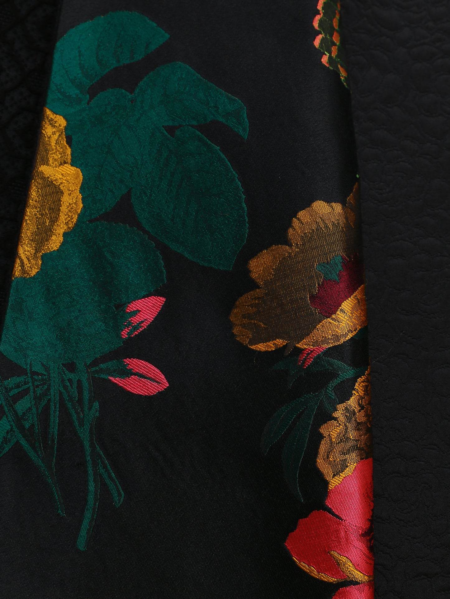 Close-up of the floral jacquard lining inside the reversible kimono jacket, showcasing vibrant botanical patterns in gold, pink, and green tones